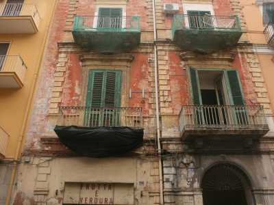 Foto 5. Percorriamo ora via Manzoni. Ci colpisce la vista di una struttura bassa, a due piani: si trova sopra un negozietto di frutta e verdura e il prospetto, un tempo rosso, � completamente corroso e con le persiane rovinate. Eppure il portone mostra ancora un elegante decoro in ferro battuto 